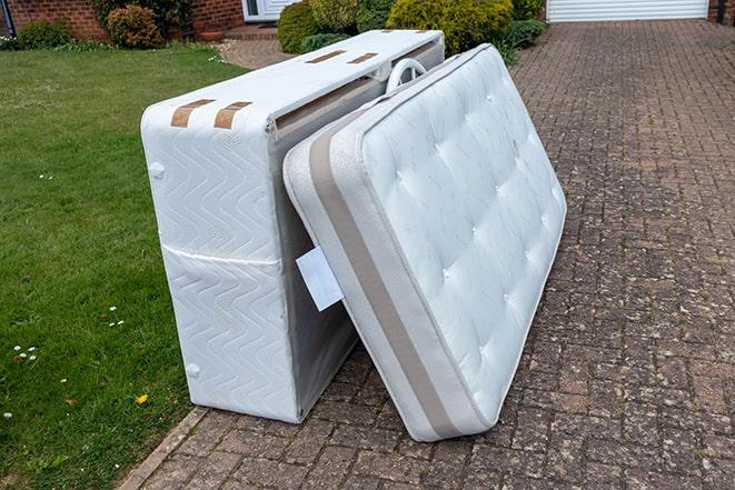 recycling center workers disposing of a used mattress