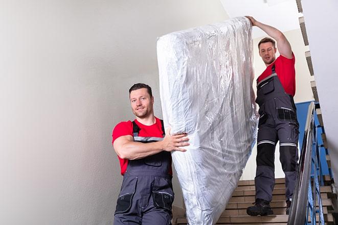 heavy lifting workers transporting a box spring out of a building in Chanhassen, MN